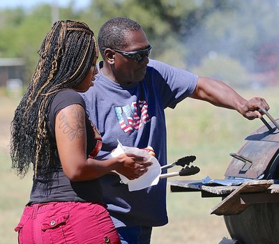 Image: Cynthia’s father, J.D. Singleton, served hot dogs and more outside Dynamic Kut’z during Customer Appreciation Day. Mr. Singleton helps Andrea Singleton in getting a snack.