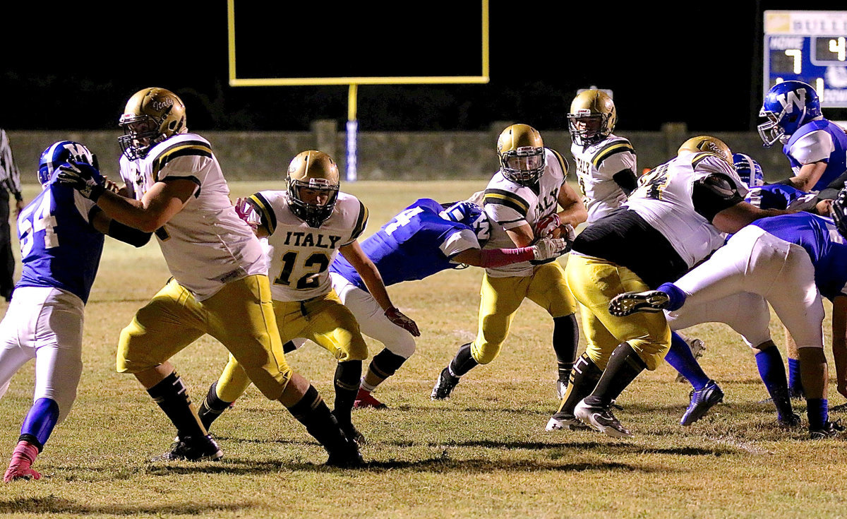 Image: Italy’s Hunter Merimon(3) tries to hit the hole created by teammates Aaron Pittmon(72), Kyle Tindol(12), and Ty Fernandez(64) against Wortham.