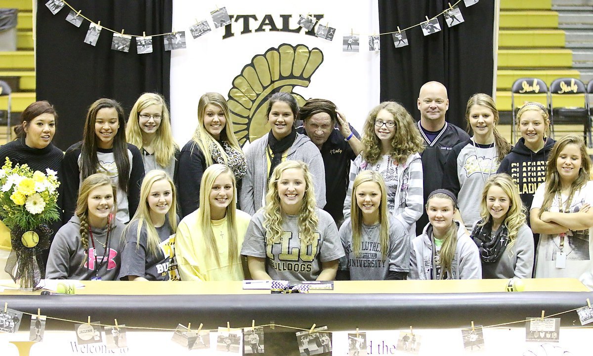 Image: Coach Jonny Jones is just one of the girls as Lady Gladiators Softball gathers for a team photo. Coach Jones is using the pony tail of Jenna Holden to blend in during the commitment ceremony held in honor of Jaclynn lewis.