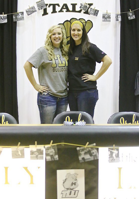 Image: Jaclynn Lewis with her big sister Megann Lewis Harlow during the commitment ceremony inside Italy Gladiator Coliseum. Between them, these fast pitch siblings will have taking the mound in Italy for a combined total of 8 years on varsity.