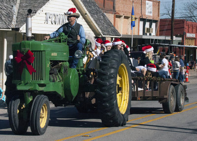 Image: Curtis Riddle, aka Santa’s Little Helper, uses a tractor to pull around a trailer full of Italy Cheerleaders.
