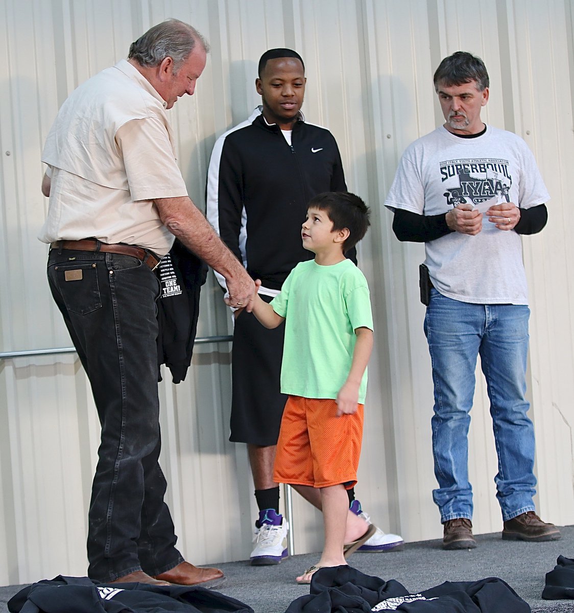 Image: IYAA C-team center Ramzi Holt(33) shakes hands with Mayor James Hobbs before recieving his Superbowl Championship hoodie. Looking on are C-team coaches Andre Speed and Gary Wood.