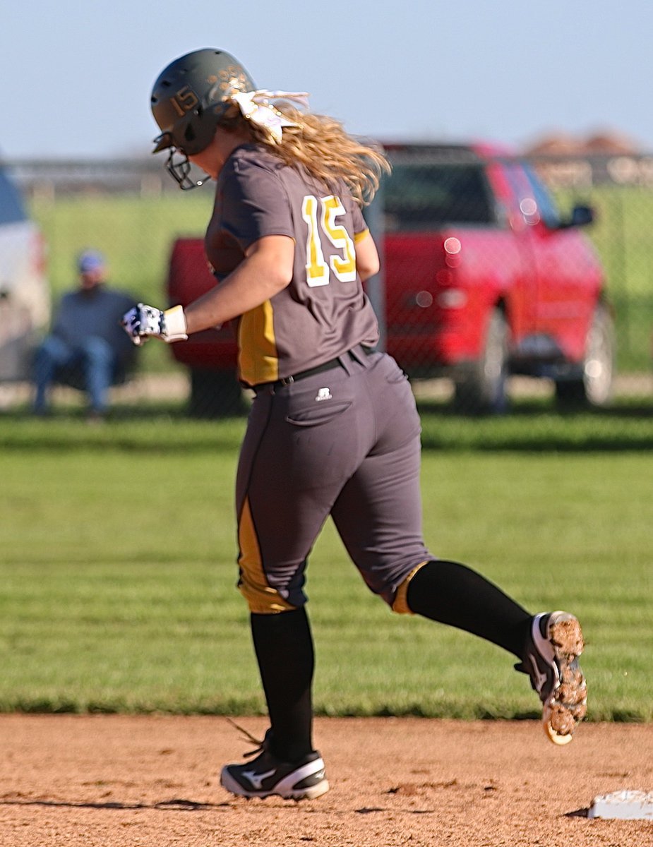 Image: Lady Gladiator Jaclynn Lewis(15) rounds second base during her homerun lap for the second time, adding insult to injury as the owner of the red truck she dented sits and watches.