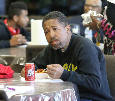 Image: Dean Reese enjoys his first bowl of chili while studying his next pot of chili to taste.