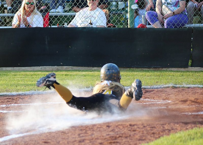 Image: Italy’s Britney Chambers(4) slides home in a cloud of dust for another Italy run.