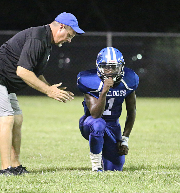 Image: Milford Bulldog head coach Ronny Crumpton talks strategy with his player #1 Taron Smith.