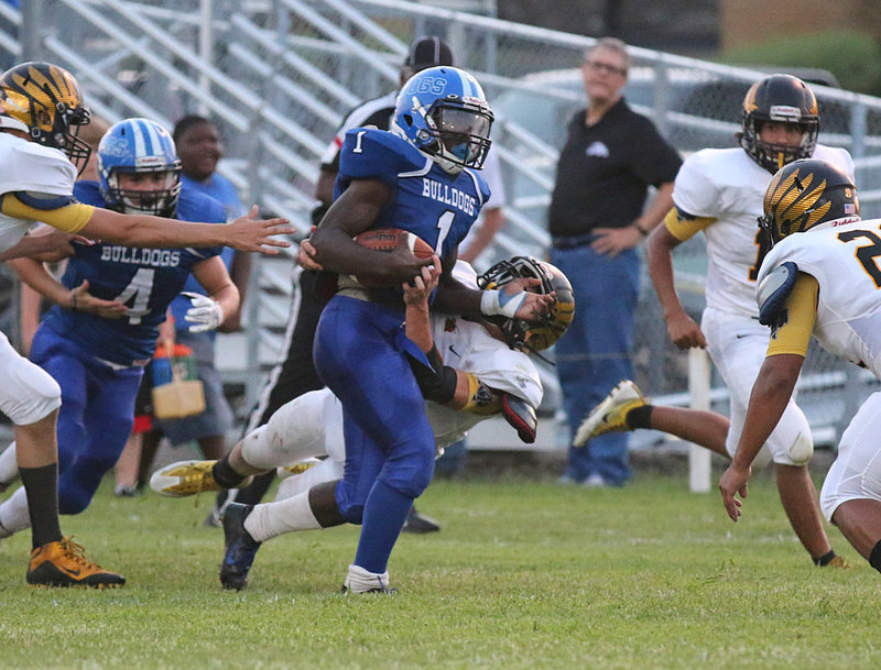 Image: Carrying the bulk of the offensive load for the 6-Man Milford Bulldogs thus far in 2016 has been sophomore #4 Taron Smith who carries a Jonesboro defender with him as he fights for more yards.