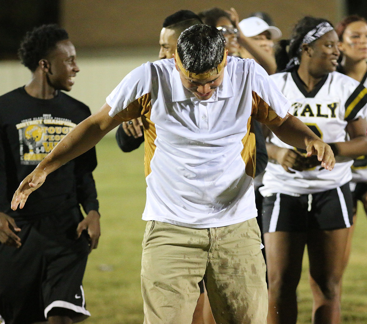 Image: Senior Girls head coach, Joe Celis, receives his celebratory water bottle bath after his Powder Puff coaching debut win. The seniors won 24-12 in a fun night of role-reversal football and cheerleading.